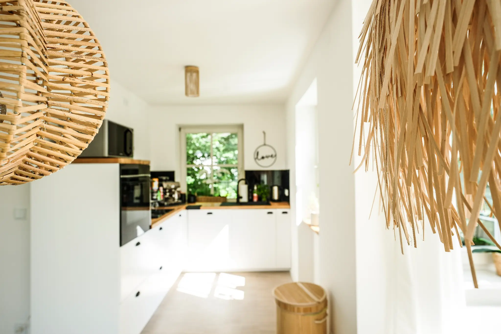 Küche mit Rattanleuchten und Blick in den Garten